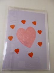 Pink heart card with eight red hearts around it.